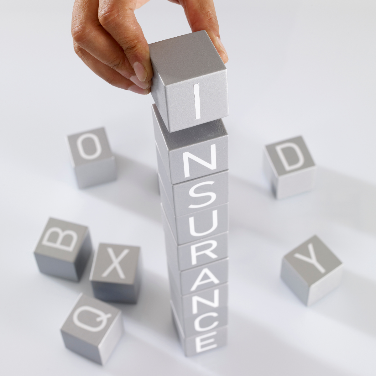 A person stacking blocks that spells out Insurance.